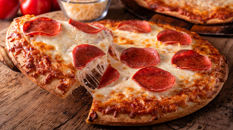 Pepperoni pizza with cheese pull on wood table