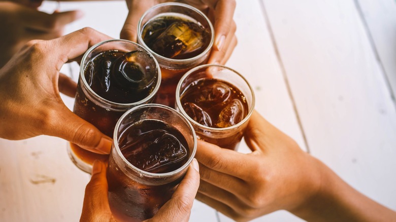 hands hold glasses of iced soda