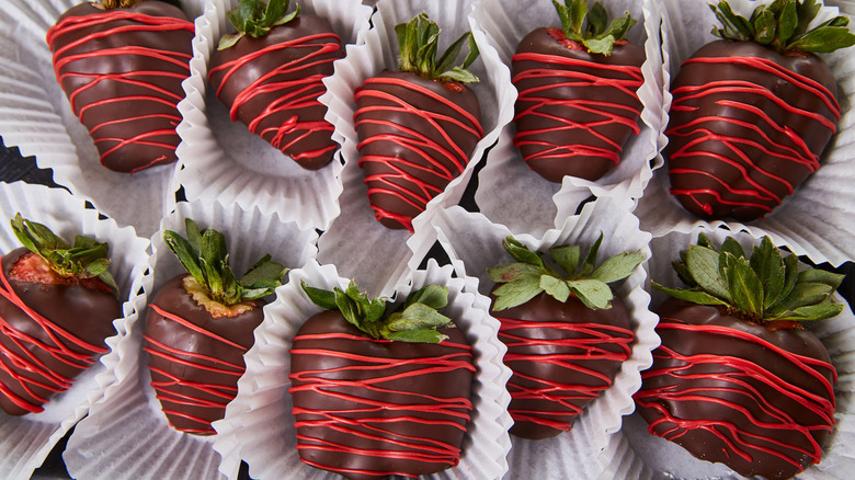 Chocolate-covered strawberries with red stirpes in paper muffin cups
