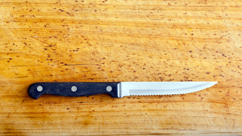Serrated steak knife on wooden surface