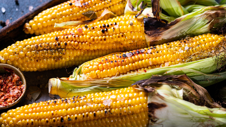 Corn on the cob with charred husks and kernels