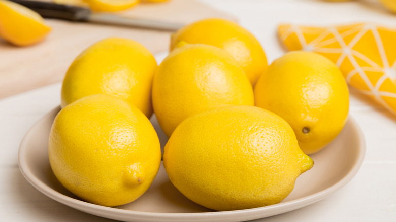 Ripe lemons resting in a shallow bowl.