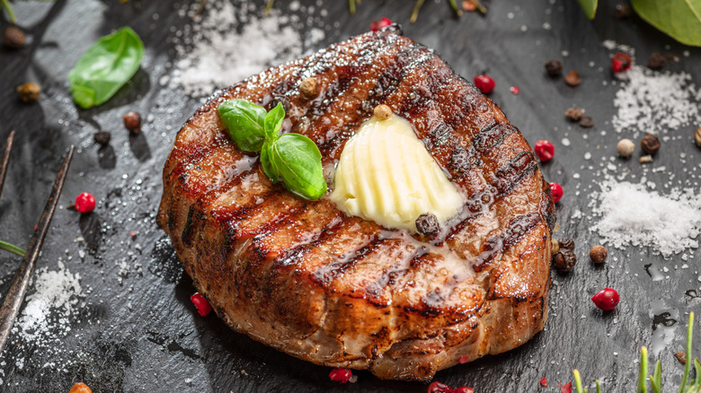 A grilled ribeye steak with a melting piece of butter atop it.
