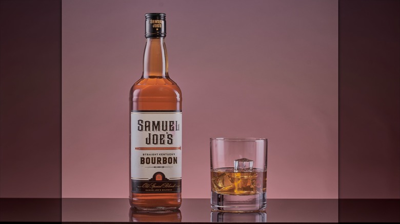 Aldi's SamuelJoe's bourbon with a glass, closeup on mauve background