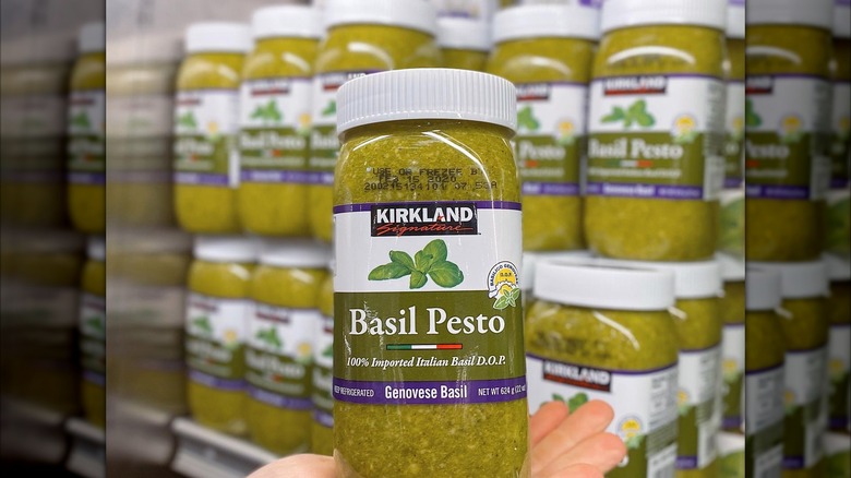 a jar of costco pesto held in a hand