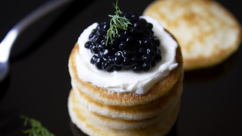 Stack of blinis garnished with caviar and creme fraiche
