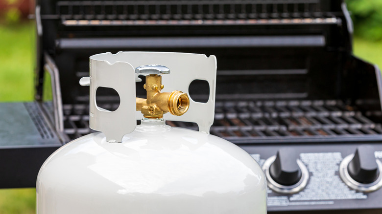 Propane tank with grill in background