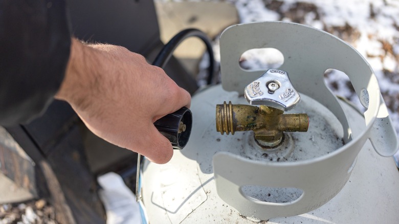 Person attaching gas line to propane tank