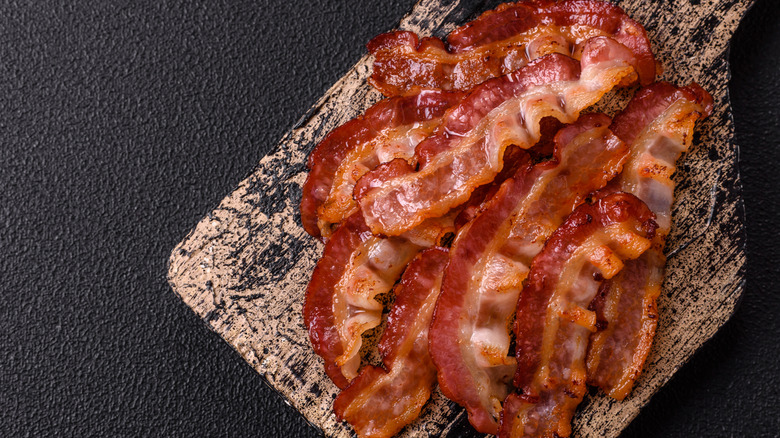 Cooked bacon strips on a wooden cutting board