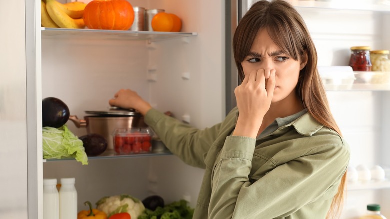 a woman covering nose from bad fridge smells