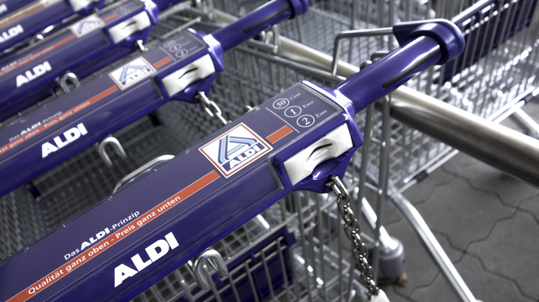 Close-up of Aldi shopping carts with dark blue handles, all chained together.