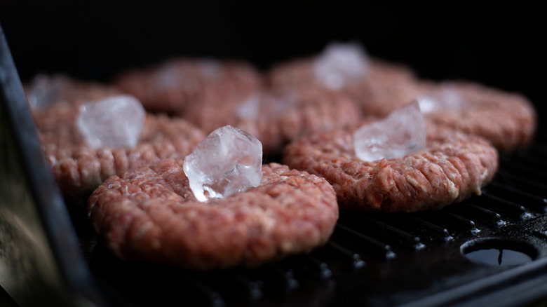 Ice cubes on raw burger patties being grilled