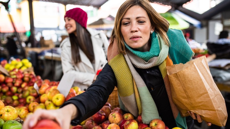 woman shops for apples at fruit stand