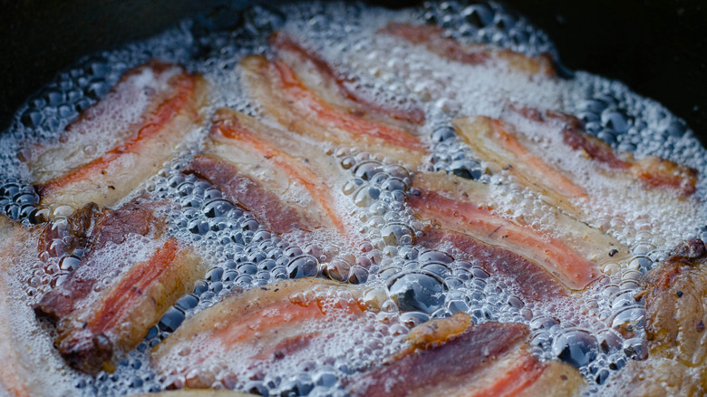 bacon frying in bacon grease in black pan