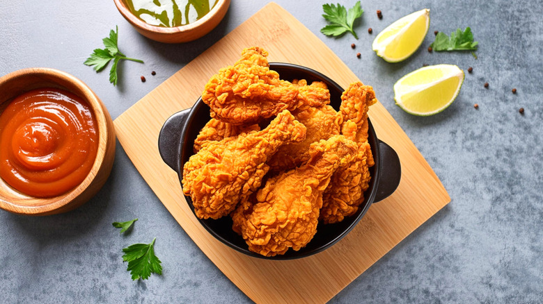 crispy fried chicken in black bowl on wooden board.