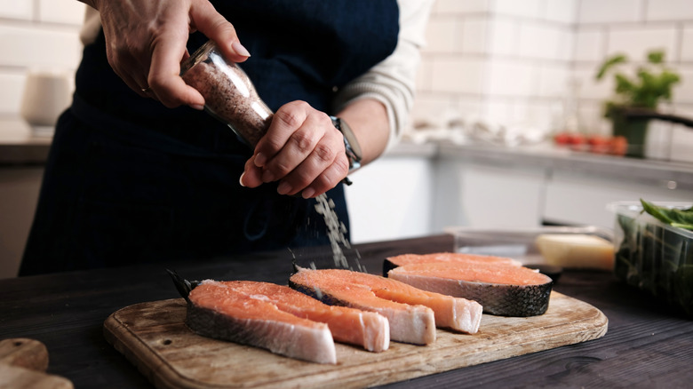seasoning raw salmon filets on wood cutting board