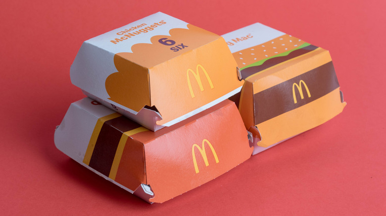 Three McDonald's food boxes are positioned on a red background