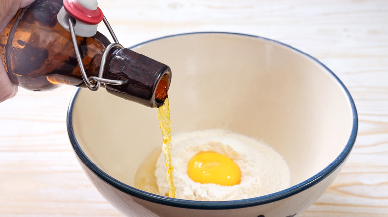 Beer being poured into a bowl to make batter for fish