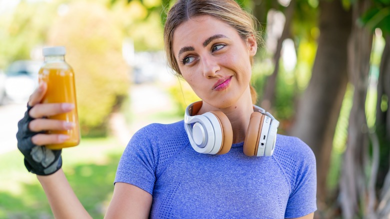woman looks skeptically at a bottle of orange juice