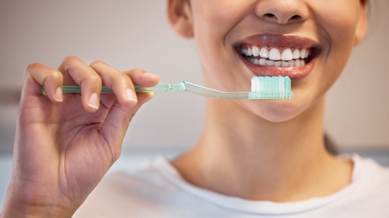 smiling person holding a toothbrush