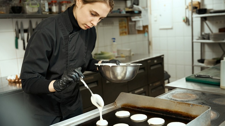 chef makes pancakes on a flat-top