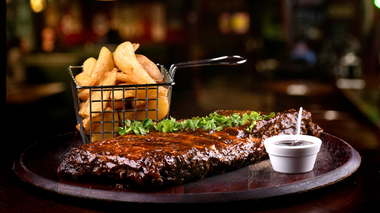 professionally-cooked ribs with fries and bbq sauce in restaurant.