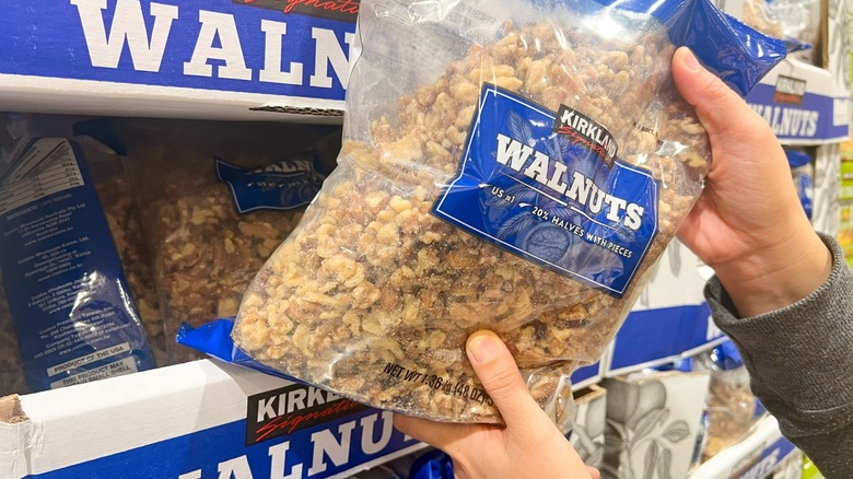 hands pull kirkland walnuts off the shelf