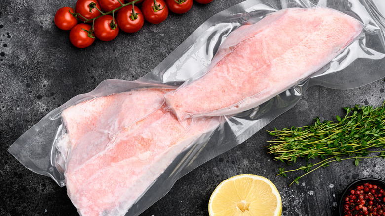 Vacuum-sealed and frozen cuts of fish with tomatoes, lemon, herbs, and berries to the side