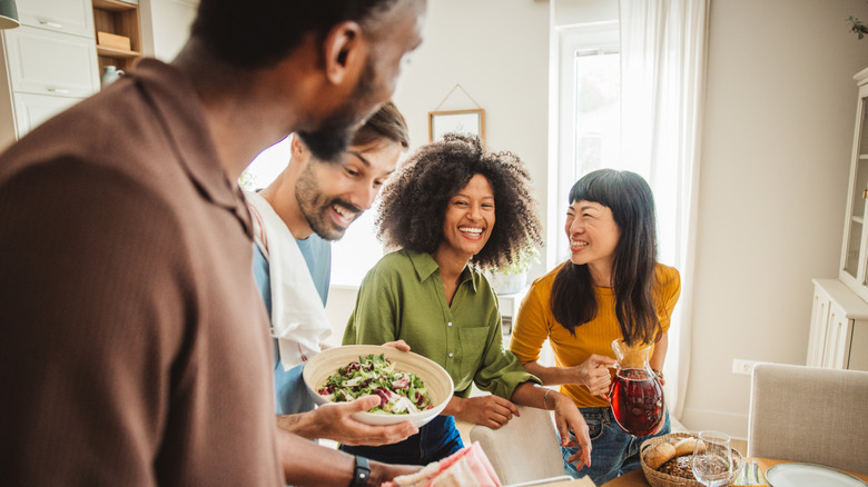 friends surround a dinner table with wine and food