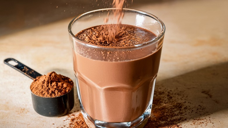Chocolate powder being added into a cup of milk.