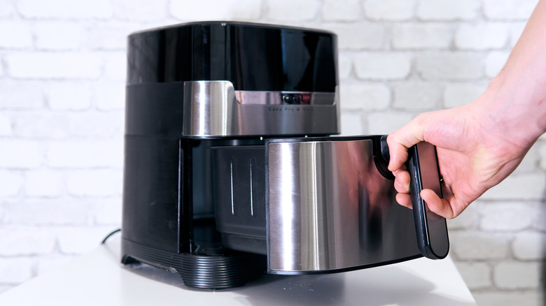 Someone pulling out air fryer tray.