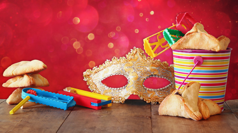 Triangular Hamantashen cookies, a mask, and toys on Purim