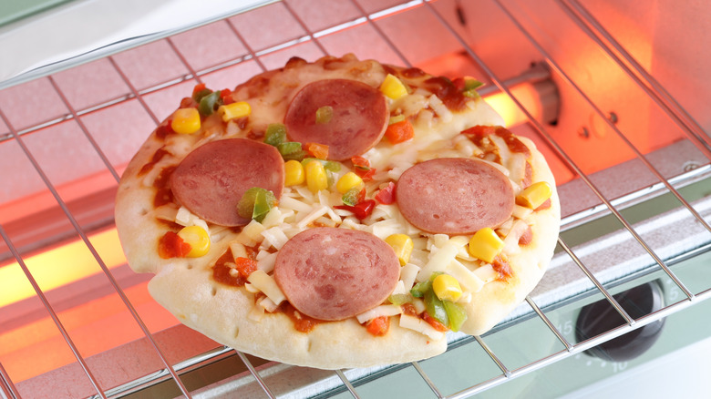 A close-up of a small frozen pizza being cooked in an electric oven