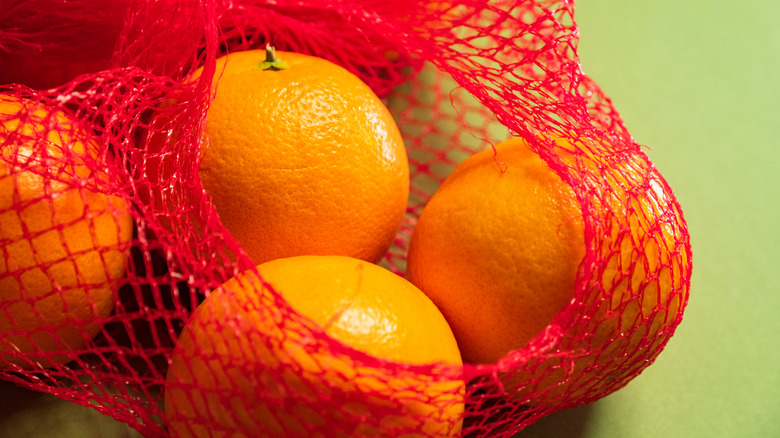 A close-up of oranges in a red plastic mesh.