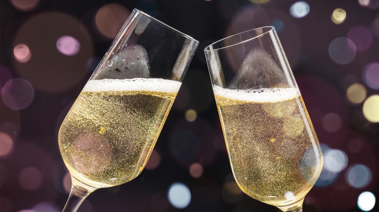 Closeup of two champagne glasses clinking on purple background