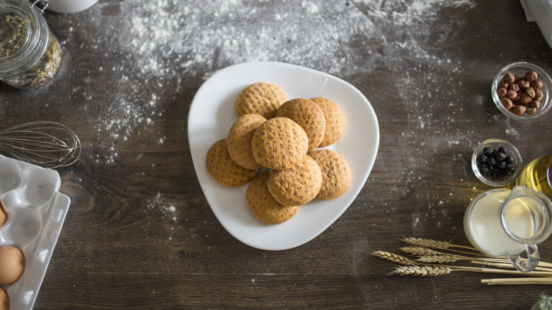 Cookies on a plate over a flour surface with other ingredients