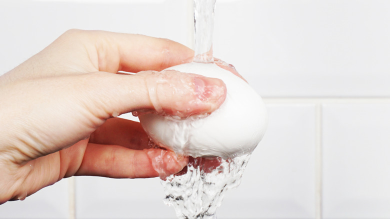 hand holding an egg under a stream of water