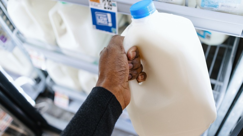 hand holds a gallon of milk