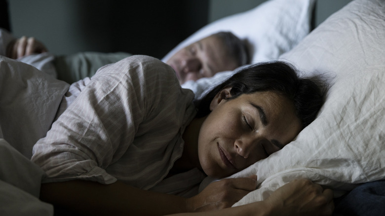 Two people sleeping side by side in bed
