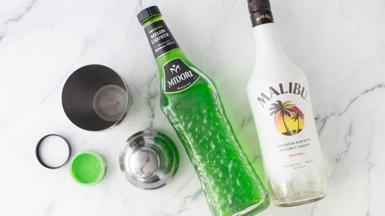 Midori and Malibu bottles next to cocktail shaker
