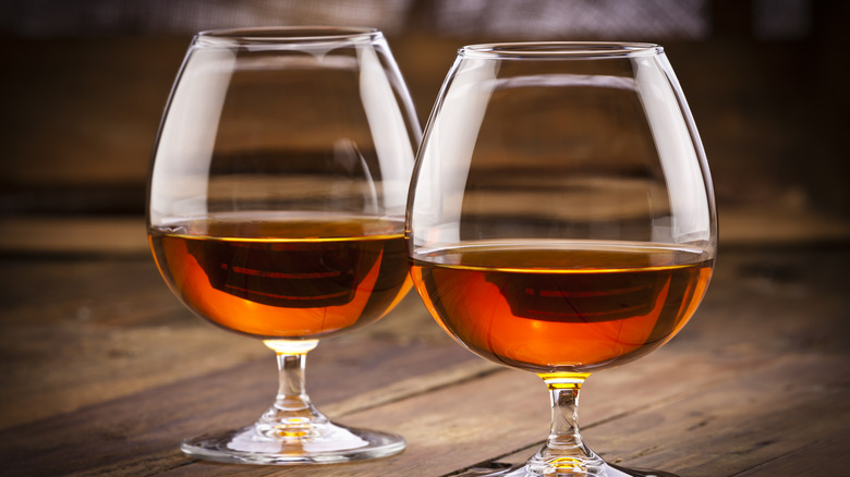 two snifters of brandy or Cognac on a wood background