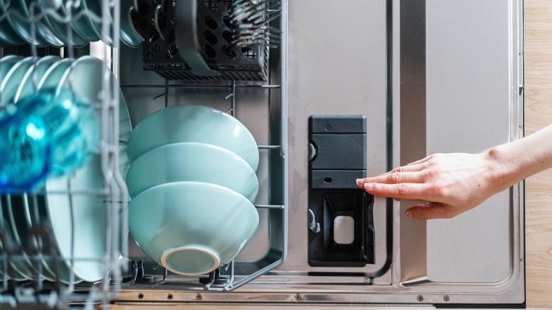 hand closing a dishwasher detergent compartment in a dishwasher