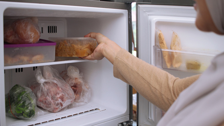 Someone taking a container of something out of a freezer