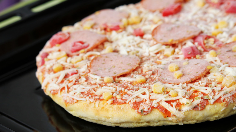 Closeup of uncooked frozen pizza with salami slices