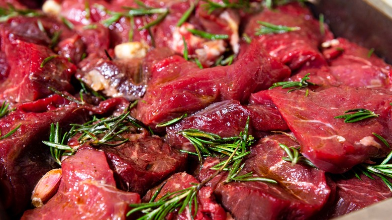 Beef marinating with garlic, herbs, and oil