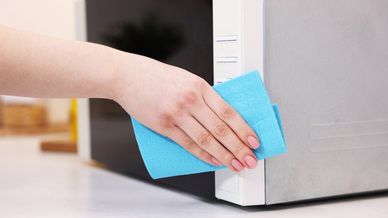 hand cleans microwave buttons