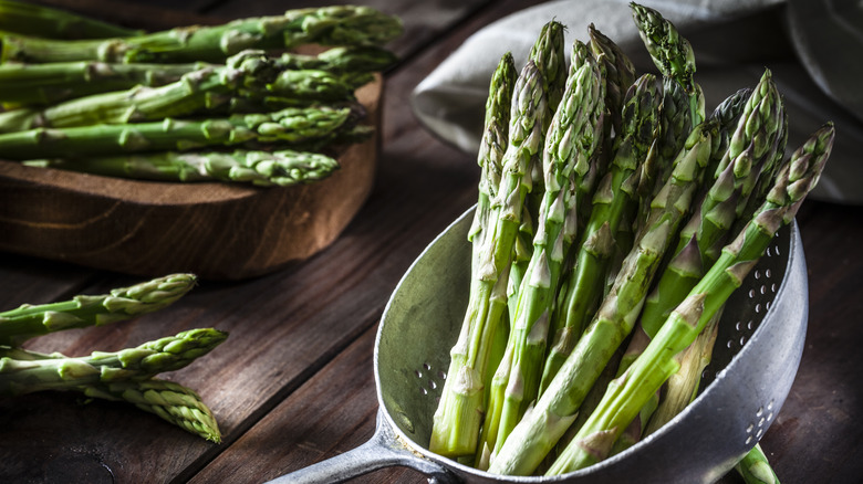 Asparagus on wood block and in colander