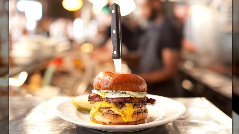 A knife sticking out of a cheeseburger from iconic Chicago restaurant Au Cheval
