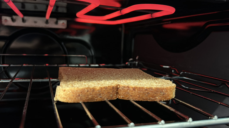 Slice of bread sitting under an electric element in an oven