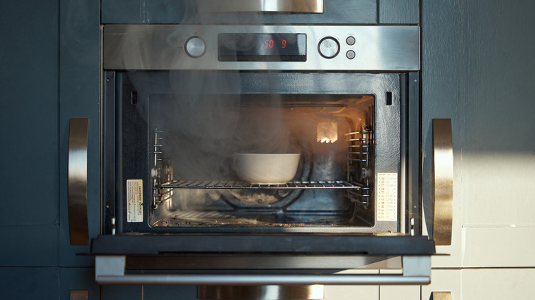 an open oven with steam coming out of it and a white bowl inside